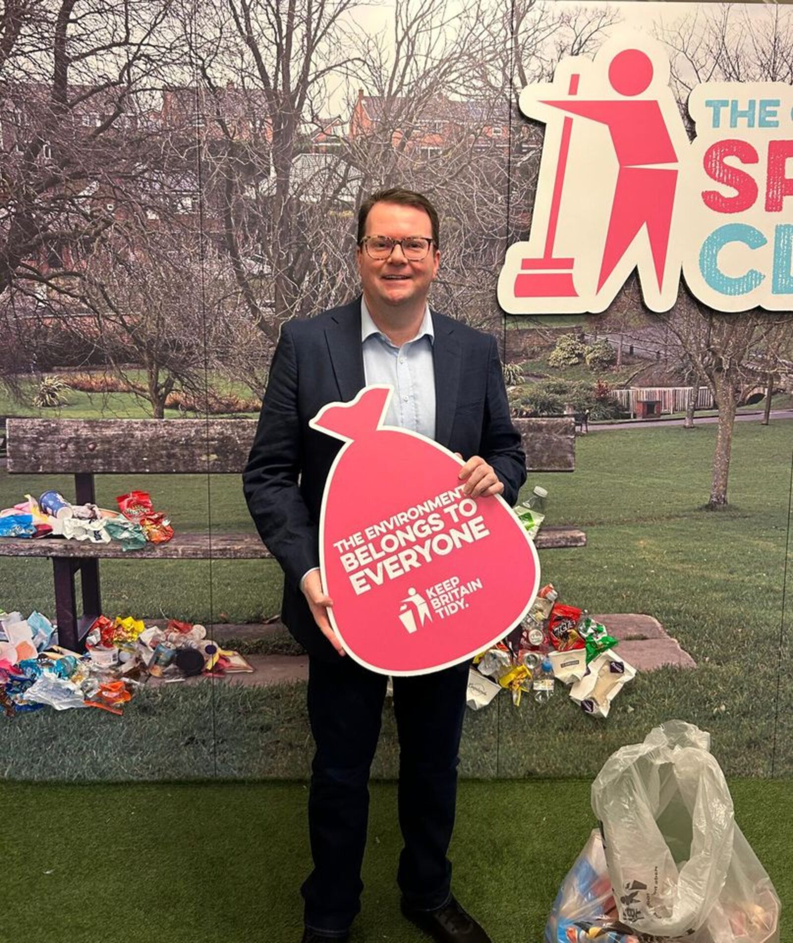 Conor McGinn MP pictured holding sign saying "the environment belongs to everyone. Keep Britain tidy"
